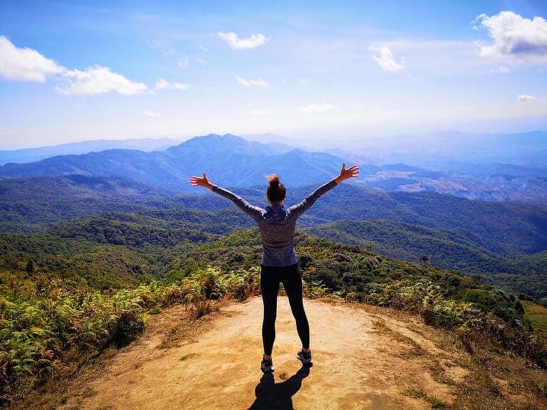 Women standing on the edge of a mountain with arms outstretched, in Doi Inthanon, Thailand