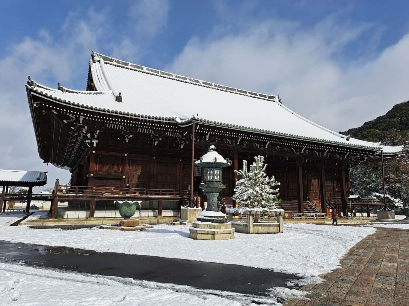 Snow covers an oversized pitched roof protrudes over the traditional wooden Chion temple in Kyoto