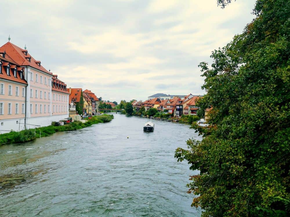 Pastel coloured buildings line either side of a wide river in Bamberg, Germany